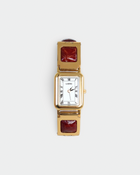 A women's rectangular analog watch with a gold-tone case, white dial with black Roman numerals, and a gold-tone link bracelet featuring square dark red inlays, shown on a light gray background.